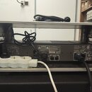 Zadní strana černého rackového zesilovače umístěného v kovovém racku. Na zařízení jsou vidět nápisy CAUTION, WARNING a SPEAKER LOADS s technickými sp…