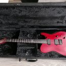 Červená elektrická kytara s matným povrchem v černém polstrovaném kufru. Na hlavě hmatníku je bílý nápis "LTD". Nástroj má dva humbuckery, jeden ovlá…