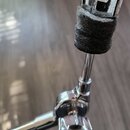 Detailní záběr na chromovaný kovový stojan s černým plstěným nebo textilním obalem v horní části. Na kovovém prvku nahoře je vyryt nápis GIBSON. Stoj…