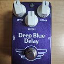 Modrý kytarový efekt s nápisy Deep Blue Delay a MAD PROFESSOR. Na horní části jsou tři bílé oválné ovladače s popisky LEVEL, REPEAT a DELAY. Ve spodn…