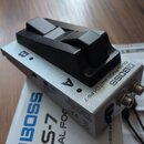 Stříbrný dvoupedálový spínač s černými plastovými plošinkami. Na horní straně je nápis DUAL FOOT SWITCH FS-7 a logo BOSS, pedály jsou označeny písmen…