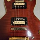 Detail elektrické kytary s červeným flamed maple povrchem a krémovým bindingem. Na snímačích jsou vidět nápisy Seymour Duncan, přičemž horní snímač n…