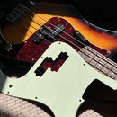 Fotografie zachycuje elektrickou basovou kytaru s barevným přechodem těla od žluté přes oranžovou k červené a černé. Nástroj má tmřečivý pickguard s…