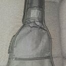 Černý textilní obal na kytaru s zipy. V dolní části je bílý nápis Fender®. Povrch materiálu vykazuje vrásnění a známky používání.