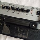 Kytarový kombo zesilovač v černém koženkovém potahu s kovovými rohy a plastovou rukojetí. Přední panel je stříbrný s nápisy INPUT, OVERDRIVE, EQ, INP…