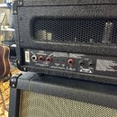 Zadní strana černého kytarového komba s kovovou mřížkou. Na zadním panelu jsou nápisy LOUDSPEAKERS, EMULATED OUT, AUDIO IN, FX LOOP a SEND RETURN. Js…