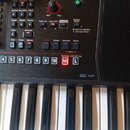 Detailní pohled na ovládací panel a klávesy digitálního klavíru. Na panelu jsou tlačítka s nápisy jako Tone, Organ, Guitar Bass, Synth, World, Drums,…