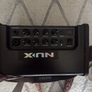 Černý kytarový zesilovač s ovládacím panelem. Na panelu jsou nápisy CHANNEL 1, VOLUME, BASS, MIDDLE, TREBLE, TUNER, CHANNEL 2, SEND, REVERB, MASTER a…