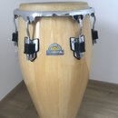 Světle hnědý dřevěný kongový buben s kovovým obručem a ladidly. Na korpusu je nalepený štít s nápisy PROFESSIONAL SERIES, MEINL a PERCUSSION. Povrch…