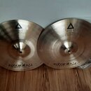 Dvě mosazné činely s viditelným broušením povrchu. Na obou je nápis istanbul Agop, logo v trojúhelníku a označení modelu XIST. Činely jsou umístěny n…