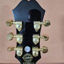 Zadní strana černé hlavy kytary se zlatými ladicími mechanismy značky GROVER. V dolní části je zlaté logo Epiphone s nápisem 2014 a textem MADE IN IN…