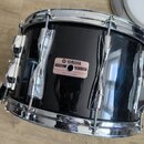 Černý buben s chromovanými obručemi a lugy. Na korpusu je nalepený růžový štítek s nápisy YAMAHA, MODEL, SER. NO. a MADE IN JAPAN. Povrch korpusu vyk…