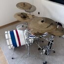 Sada cymbálů značky Anatolian na chromovaných stojaních. Cymbály mají zlatavou barvu s viditelnými stopami po používání a nápisem Anatolian. V pozadí…