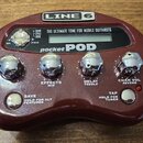 Vínový efektový procesor s nápisy LINE 6 a pocket POD. Zařízení má čtyři chromované otočné ovladače s popisky EFFECTS MID, DELAY TREBLE a CHAN VOL RE…