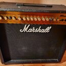 Černý kytarový kombo zesilovač značky Marshall, model MG100DFX. Horní ovládací panel je zlatý s řadou otočných knoflíků rozdělených do sekcí Clean Ch…