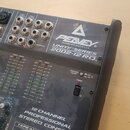 Šedý míchací pult s nápisy PEAVEY, DESIGNED AND MADE IN U.S.A., UNITY SERIES a 2002-12 RQ. Na předním panelu jsou vidět různé konektory, přepínače a…