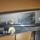 Detailní záběr na zadní část černého zařízení s identifikačním štítkem. Na štítku je text: TRUE DIVERSITY RECEIVER Em100 G2, FREQ.RANGE 830-866 MHZ,…