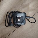 Černý efekt pedál s kovovým šedým povrchem a nápisem FENDER. Na přední straně je umístěn stříbrný spínač a v dolní části nápis PN 770. K zařízení jso…