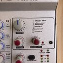 Detailní záběr na ovládací panel stříbrného audio zařízení. Na panelu jsou nápisy TAPE IN, TAPE OUT a RIGHT u konektorů, sekce EQ s ovládacími prvky…