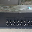 Černý rackový přístroj s nápisem LIVE a logem v podobě stylizovaného písmene M. Na horní straně je šedý grafický vzor vln. Přední panel obsahuje řadu…