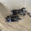 Dvě černé kovové mechanismy pedálů s chromovanými tyčemi. Povrch je v několika místech odřený a znečištěný prachem. Na předmětech nejsou žádné vidite…
