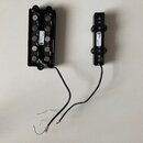 Dvě černé elektrické snímače s magnety, jeden širší a jeden užší. Na širším snímači je bílá nálepka s nápisy „WW204“ a „1601“, v dolní části je malé…