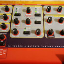 Detailní pohled na ovládací panel červeného syntetizátoru s nápisem 16 VOICES 4 OUTPUTS VIRTUAL ANALOG SYNTHESIZER. Panel obsahuje sekce OSCILLATORS,…