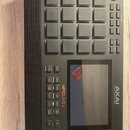 Černý sampler MPC Live II s mřížkou 16 gumových padů a dotykovým displejem. Na přední straně je svisle napsáno MPC LIVE II a AKAI PROFESSIONAL. Zaříz…