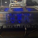 Zadní strana černého kytarového komba s texturovaným povrchem a modrým podsvícením vnitřku. Na zadním panelu je nápis MESA a text VACUUM TUBE AMPLIFI…