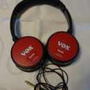 Černá sluchátka s červenými kruhovými mušlemi. Na obou mušlích je bílý nápis VOX, pod ním slovo BASS a v dolní části text Produced by audio-technica.…