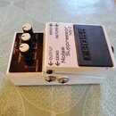 Bílý kytarový pedál značky BOSS s nápisem Noise Suppressor NS-2. Na horní straně jsou tři ovládací knoflíky a nápisy THRESHOLD, REDUCTION a MODE. Na…