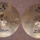 Dvě mosazné činely značky Zildjian. Levý činel nese nápisy A CUSTOM a HIHAT BOTTOM 14" 35,56 cm. Pravý činel má nápisy A CUSTOM a HIHAT TOP 14" 35,56…