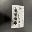 Stříbrný 4kanálový sluchátkový zesilovač s kovovým povrchem. Na zařízení je nápis „4-CHANNEL STEREO HEADPHONE AMPLIFIER“ a logo „Millenium AMP HA400“…