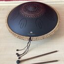Černý kovový tongue drum s dekorativním ornamentem v horní části. Na povrchu je bílý nápis „Sonic Energy“ a nad ním logo znázornující dvě stylizované…