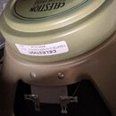Detail zadní strany reproduktoru v olivově zelené barvě. Na horní části je vidět logo CELESTION a níže bílá nálepka s nápisy CELESTION, T5647B G10 GR…