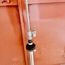 Detail stříbrného kovového stojanu s teleskopickým mechanismem a utahovacím šroubem. V místě spoje je vidět černý gumový nebo plastový prstenec a zná…