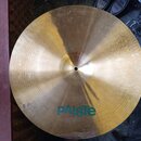 Kruhový mosazný činel s viditelným opotřebením povrchu a šmouhami. Na horní části je modrý nápis paiste. Činel leží na podkladu, kde jsou vidět části…