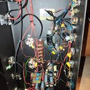 Fotografie zachycuje vnitřní zapojení elektroniky hudebního přístroje. Je vidět množství barevných vodičů, kondenzátory, potenciometry a několik prin…