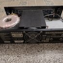 Fotografie znázorňuje otevřený zadní panel černého zesilovače značky BEHRINGER, model BX4410. Uvnitř jsou vidět komponenty, konkrétně velký toroidní…