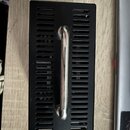 Černý kovový box s ventilačními otvory v podobě vodorovných rýh. Uprostřed je připevněna stříbrná kovová rukojeť. Povrch vykazuje drobné nečistoty a…