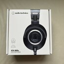 Bílá kartonová krabice s černými sluchátky. Na krabici je v horní části logo a nápis audio-technica, ve spodní části označení ATH-M50x a text Profess…