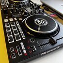 Černý DJ kontrolér značky Numark s modelem MIXTRACK PRO FX. Zařízení má dva jog-kola, fader, zahlreiche bílé tlačítka a ovládací knoflíky. Povrch je…