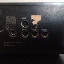 Záběr na zadní stranu černého audio zařízení. Jsou zde vidět konektory s popisky MICRO, RADIO, TAPE a PHONO, dále výstupy označené 500 Ω / 100 V a 4-…