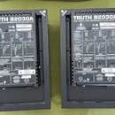 Dva černé studiové monitory z pohledu zezadu. Na obou je nápis TRUTH B2030A HIGH-RESOLUTION REFERENCE STUDIO MONITOR. Levý kus má kód N11999 a Date C…