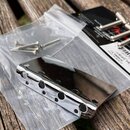 Stříbrný, chromovaný kovový most na elektrickou kytaru s šesti sedly. Příslušenství obsahuje sáček s několika montážními šrouby a černý papírový obal…