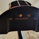 Fotografie zachycuje zadní část hlavy strunového nástroje v černé barvě. Uvnitř vyřezaného prostoru je vidět nápis MADE IN THE CZECH REPUBLIC (EU). J…