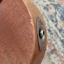 Detailní pohled na spodní část dřevěného hudebního nástroje s připevněným kovovým krytem jackového vstupu. Kovový kryt je přišroubován dvěma šroubky…