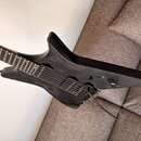 Černá elektrická kytara s matným povrchem a výraznou strukturou dřeva. Nástroj má dva humbuckery, jeden ovládací knoflík a přepínač. Na těle nejsou v…