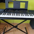 Černý digitální klavír značky YAMAHA umístěný na černém X-stojanu. Na ovládacím panelu je vidět logo YAMAHA a označení modelu PSR-E270. Nástroj má př…