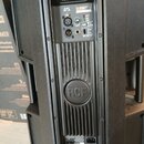 Zadní strana černého aktivního reproduktoru. V horní části je ovládací panel s nápisem ART 715-A, dvěma XLR vstupy a ovratem VOLUME. Uprostřed je pla…